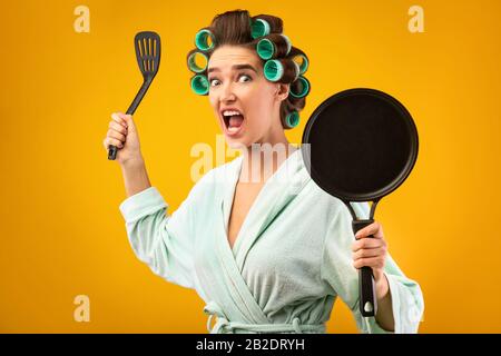 Crazy Housewife Holding Frying Pan And Shouting Posing In Studio Stock Photo