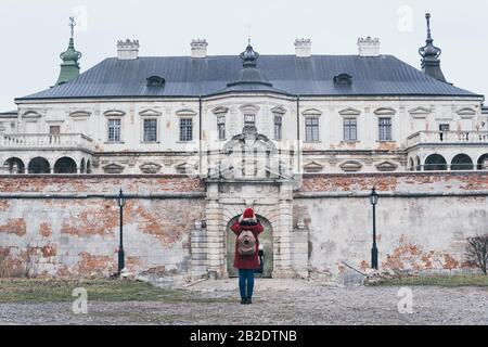 Pidhirtsi, Ukraine - December 2019: Woman in red coat taking picture of Pidhirtsi Castle in Lviv region. Stock Photo