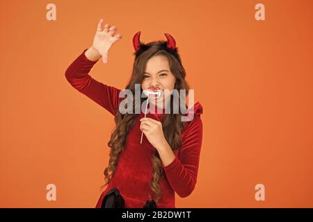 Halloween costumes. Photo booth props. Vampire teeth. Little girl cute small horns celebrate Halloween. Carnival concept. Small child imp style accessory. Halloween party. Trick or treat concept. Stock Photo