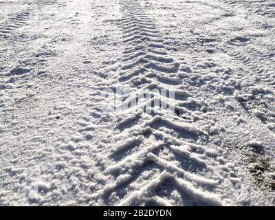 Traces of car tires in the snow in the light of the bright sun Stock Photo