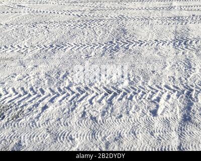 Traces of car tires in the snow in the light of the bright sun Stock Photo