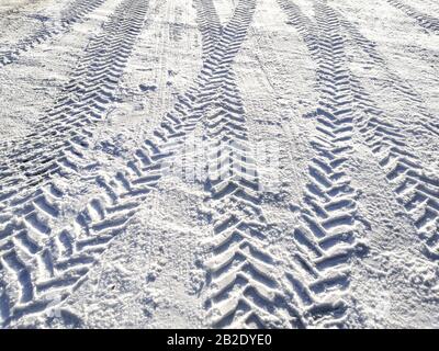 Traces of car tires in the snow in the light of the bright sun Stock Photo