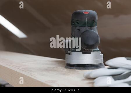 Carpentry. Wood sanding. Orbital sander for woodworking. In a natural light Stock Photo