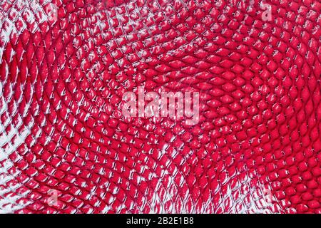 Abstract red patent leather texture with lighter highlights, embossed rhombuses on the surface, bright design background Stock Photo