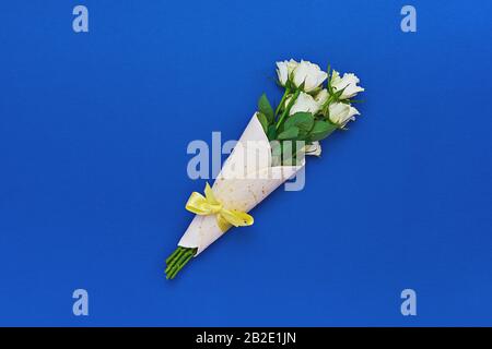 Bouquet of white roses wrapped in tortilla on classic blue background. Concept of edible, zero waste or eco-friendly gift wrapping Stock Photo