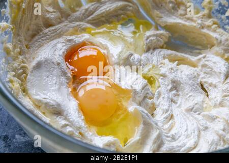 Two eggs with different coloured yolks are added to cake mixture. Stock Photo