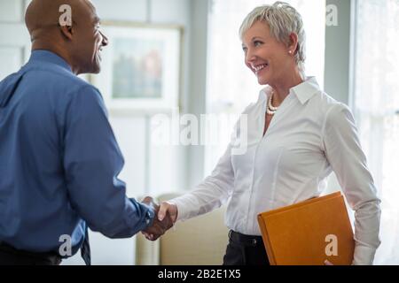 Smiling mature woman shaking hands with a business client Stock Photo