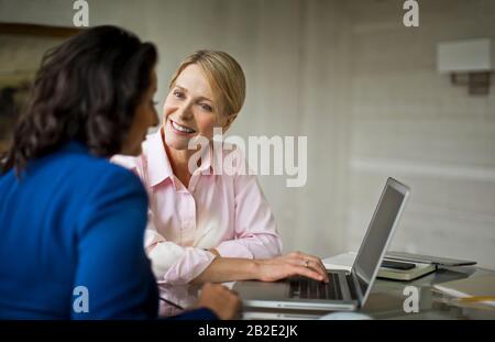 Two female colleagues talking at the office Stock Photo