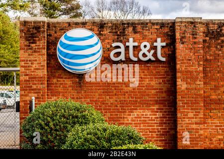 Charlotte, NC/USA - December 14, 2019: Medium horizontal shot of 'AT&T' brand and logo mounted on a red brick wall with trees, parked cars and storm c Stock Photo