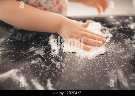 children's pen prepares homemade cakes, sprinkles with sugar on a black background by baking for the oven Stock Photo
