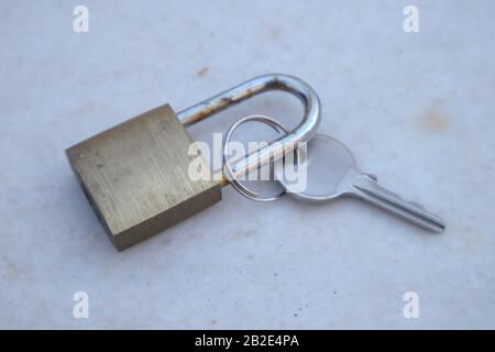 Close-up of a padlock next to the key that opens it on a weathered gray marble surface Stock Photo