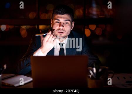 Businessman Using Voice Assistant On Mobile Phone Sitting In Office Stock Photo