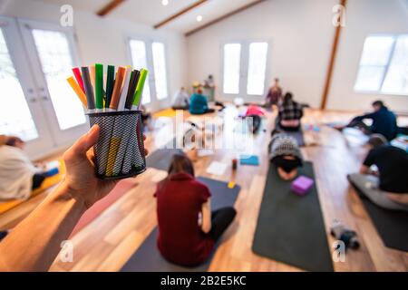 The hand of the person holding a jar of multi-colored pencils. POV view. A yoga trainer offering to his students to take pens Stock Photo