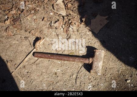 Old dirty iron hammer lies on the ground. Stock Photo