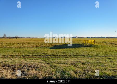 Grass field and old yellow signal number on the former landing field of Tempelhof park, previous airport, in Berlin, Germany Stock Photo