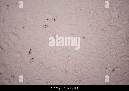 Texture of colored pale pink plaster of the wall in the form of drops, holes, contrasting. Unusual vision of simple things. Background Stock Photo