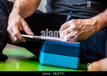 The man writing something about yoga on a copybook. The man learning a new things and making some notes on his notebook. A writing guy Stock Photo