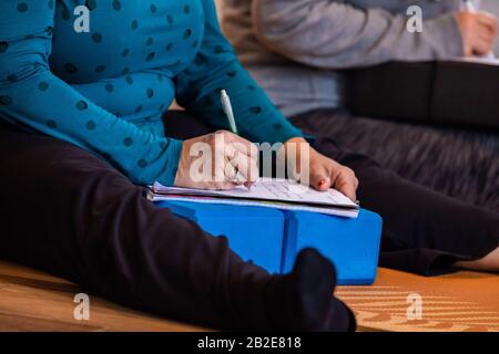 A medium-shot photo of people making some notes on their notepads during a yoga class. The couple making some notes in yoga Stock Photo