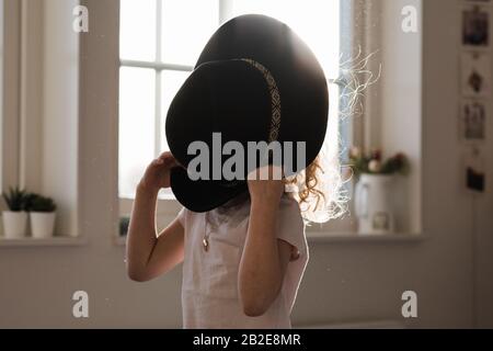 portrait of a young girl playing with a hat covering her face Stock Photo
