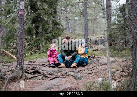 dad having a snack with his kids whilst outside hiking Stock Photo