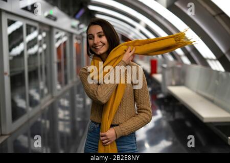 Young woman putting on a yellow scarf on the subway. Yellow scarf concept. Stock Photo