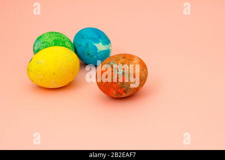 Four multi-colored Easter eggs on pink background top view, space for text. Concept happy easter day. Stock Photo