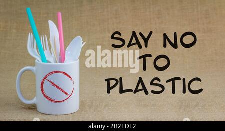 Say No to Plastic text next to single use plastic items in mug, refuse single use plastic cutlery and straws. Stock Photo