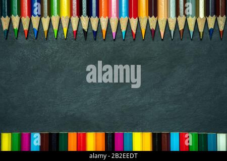 Colored pencils on chalkboard background. Top view and copy space. Concept of art education. Stock Photo