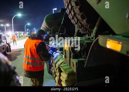 03 March 2020, Saxony-Anhalt, Burg: A soldier of Logistics Battalion 171 refuels a US Army vehicle in Clausewitz Barracks. The military vehicle is being transferred from a depot in Belgium to Poland for the US-led exercise 'Defender Europe 2020' and was refuelled at the site by Bundeswehr soldiers. As part of the large-scale exercise, around 20,000 soldiers are to be transferred from the USA across Germany to Eastern Europe. In addition, several more exercises are planned in Germany, Poland, Georgia and the Baltic States, bringing the total number of soldiers from 18 nations involved to 37,000 Stock Photo