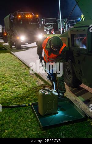 03 March 2020, Saxony-Anhalt, Burg: A soldier of Logistics Battalion 171 fills a spare canister for a US Army vehicle. The military vehicle is being transferred from a depot in Belgium to Poland for the US-led exercise 'Defender Europe 2020' and was refuelled at the site by Bundeswehr soldiers. As part of the large-scale exercise, around 20,000 soldiers are to be transferred from the USA across Germany to Eastern Europe. In addition, several more exercises are planned in Germany, Poland, Georgia and the Baltic States, bringing the total number of soldiers from 18 nations involved to 37,000. Ph Stock Photo