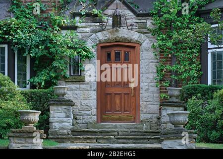 elegant wooden front door of stone house with flower pots and vines ...