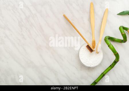 Bamboo toothbrush, bamboo plant dentifrice tooth powder on white marble background.Flat lay copy space.Biodegradable natural bamboo toothbrush.Eco Stock Photo
