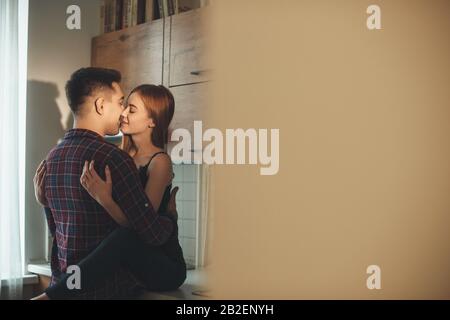 Lovely caucasian couple kissing each other in the kitchen before having a breakfast Stock Photo