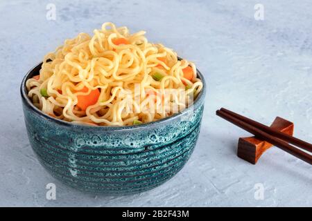 Instant noodles bowl with carrot and scallions, vegetable soba bowl with chopsticks and copy space Stock Photo