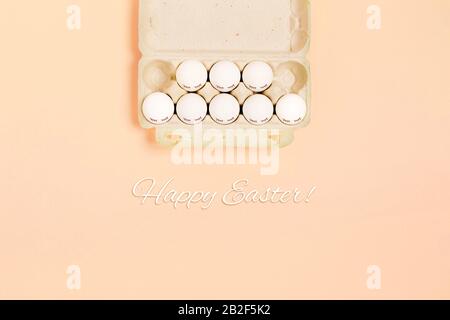 Happy Easter. White eggs with painted eyes in paper packaging on yellow background. Flat lay, top view, copy space. Stock Photo