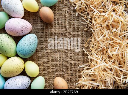 Easter eggs on a sackcloth and straw . Happy Easter  multicolored  easter eggs. Background with easter eggs. Flat lay, top view. Stock Photo