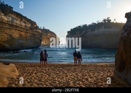 Couples enjoying sunset at the shoreline. At Loch Ard Gorge along the Great Ocean Road, Victoria, Australia. Stock Photo