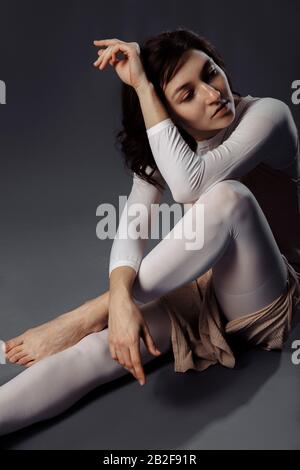 The girl is sitting in a suit for an LPG massage with hands and legs clasped together. Stock Photo