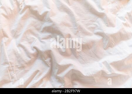 Close up white bedding sheets and pillow in hotel room at morning time with sunlight from windows Stock Photo