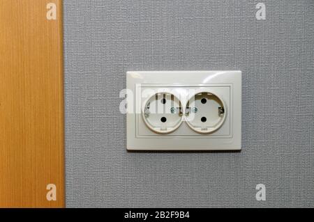 Single empty electrical outlet on a gray wall by the doorway. Europe Stock Photo