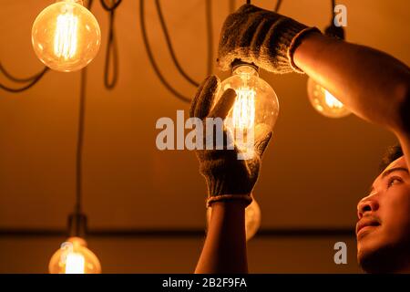 Asian man / house owner cleaning or changing vintage light bulb. House maintenance concept Stock Photo