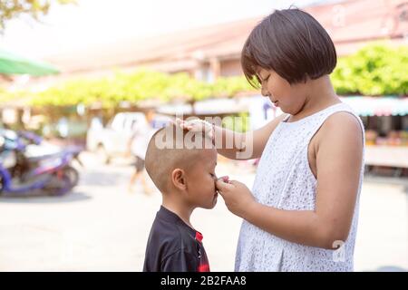 Young asian boy crying and his old sister try to encourage. Take care to young brother concept Stock Photo