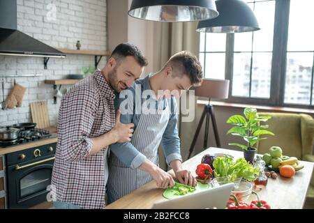 Young men standing at the table in the kitchen preparing breakfast. Stock Photo