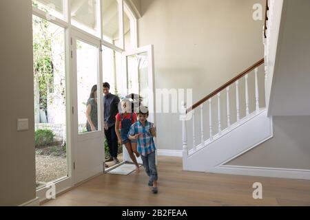 Front view of a Caucasian couple and their young son and daughter entering the front door of their new home, the children running ahead Stock Photo