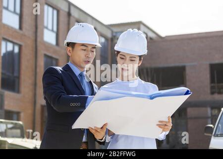 Two architects talking over blueprints Beijing China Stock Photo