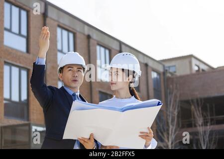 Two architects talking over blueprints Beijing China Stock Photo