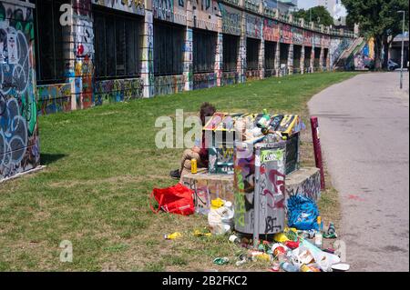 16.06.2019, Vienna, Austria, Europe - A homeless man sits next to an overflowing dustbin in the centre of the Austrian capital city. Stock Photo