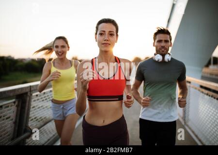 Athletic fit people exercising and running together outdoors Stock Photo
