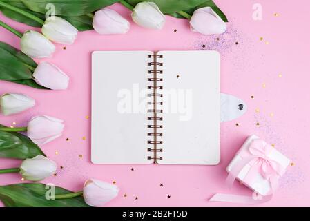 Pastel Tulips with notebook and gift box on pink background with stars, copy space Stock Photo
