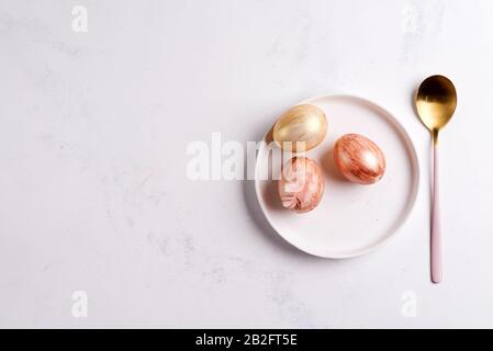 Easter table setting from above. Elegant empty plate, cutleryand golden eggs on stone Stock Photo